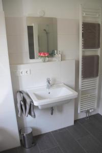 La salle de bains blanche est pourvue d'un lavabo et d'un miroir. dans l'établissement Chiemsee-Edelweiß Ferienwohnung, à Prien am Chiemsee