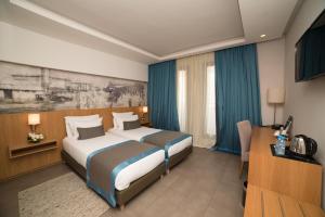 pokój hotelowy z 2 łóżkami i telewizorem w obiekcie ONOMO Hotel Rabat Terminus w mieście Rabat