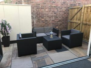 een patio met banken en tafels en een bakstenen muur bij No 4 Elizabeth Street in Congleton