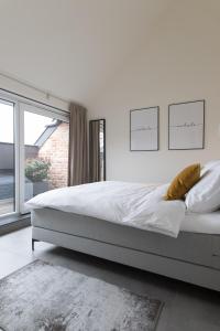 a white bedroom with a large bed and a window at Raveel Lofts in Deinze