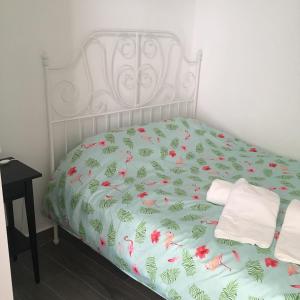 a white bed with a green and pink bedspread at Casinha in Faro