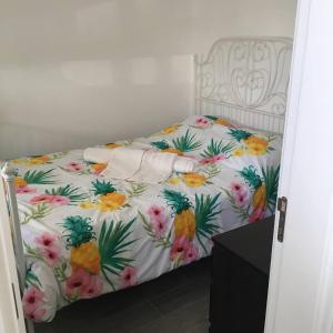 a bed in a room with a floral bedspread at Casinha in Faro