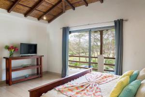 Schlafzimmer mit einem Bett, einem TV und einem Fenster in der Unterkunft Town House 9 in Iguana