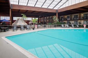 a large swimming pool in a hotel with tables and chairs at Boxboro Regency in Boxborough