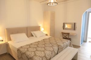 1 dormitorio con cama, mesa y espejo en Theasis Luxury Suites, en Schinoussa