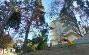 a building on a hill with a ladder next to trees at Departamento reñaca bosque in Viña del Mar