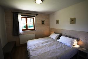 a bedroom with a bed with white sheets and a window at Gaber B&B in Gabrovizza San Primo