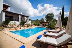 a swimming pool with lounge chairs and a house at Villa Ca na Vinya in Cala Tarida