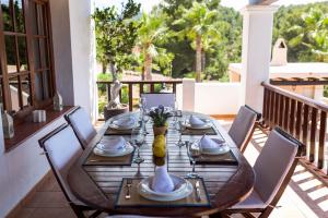 a wooden table with chairs on a balcony with a tableablish at Villa Ca na Vinya in Cala Tarida