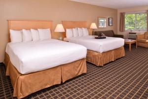 a hotel room with two beds and a living room at Campus Inn & Suites Eugene Downtown in Eugene