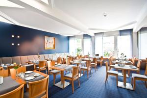 a restaurant with tables and chairs and windows at Ringhotel Ahrensburg in Ahrensburg