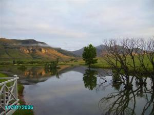un lago con alberi e montagne sullo sfondo di Royal Coachman a Clarens