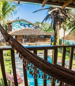 a hammock in front of a resort with a pool at Pousada Tubes Maresias in Maresias