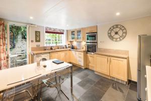 una cocina con armarios de madera y un reloj en la pared en The Garden Flat en Londres