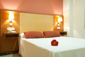 a hotel room with a bed with a flower on it at Apartamentos Turísticos Los Girasoles II in Granada