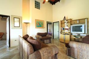 a living room with couches and a flat screen tv at Sungold House Barbados in Saint Peter