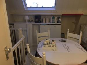 una cocina con una mesa y sillas blancas y una ventana en Gezellige zolder in Wassenaar met dakterras, en Wassenaar