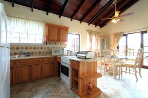 a kitchen with wooden cabinets and a dining room at Sungold House Barbados in Saint Peter