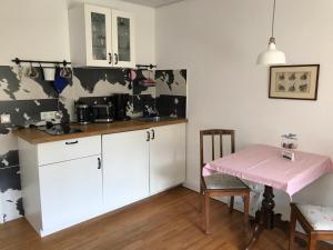 eine Küche mit weißen Schränken und einem rosa Tisch in der Unterkunft Ferienwohnungen im Lüftlmalereck, Mussldomahaus in Oberammergau
