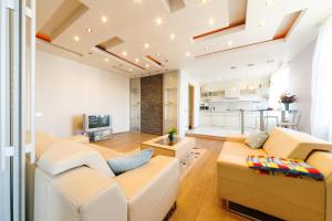 a living room with white furniture and a kitchen at Brivibas LUX in Riga +19 photos
