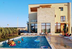 a group of people in a swimming pool in front of a building at Sara in Vama Veche