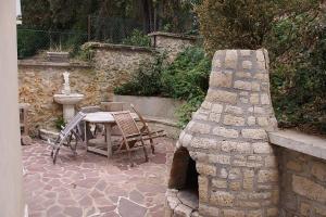 d'une terrasse avec une table et une cheminée en pierre. dans l'établissement Appartement 2 pièces neuf et indépendant, à Jouy-en-Josas