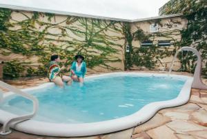 two young people sitting in a swimming pool at Pousada Familia Ottoboni in Cananéia