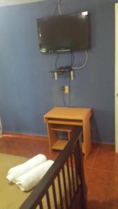 um quarto com uma mesa, uma televisão e uma cama em Hospedaje Rampolla's em Volcán