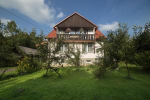 a house with a balcony on top of a yard at Pokoje Gościnne "SOSENKA" in Cisna