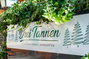 een bord voor de tuin met een plant bij Hotel Drei Tannen in Moosburg
