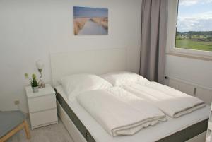 a bedroom with a bed with white sheets and a window at Penthousewohnung mit WLAN - Ostseeblick zur Sonnenseite in Damp