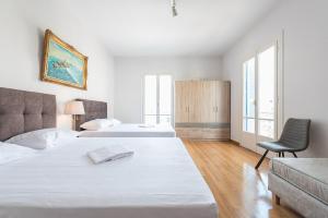 2 łóżka w białym pokoju z krzesłem w obiekcie Victoria Majesty Apartments w Atenach