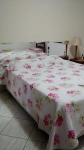 - un lit avec une couverture rose et blanche et des fleurs roses dans l'établissement Casa de Férias Mãe Maria, à Aparecida