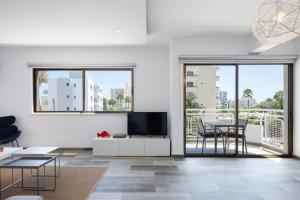een woonkamer met een tv en een tafel en stoelen bij The Jolo in Limassol