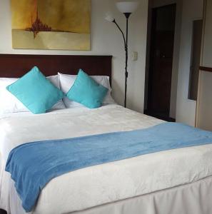 Una gran cama blanca con almohadas azules. en Casa Echavarria, en San José