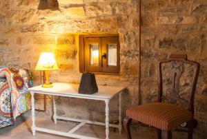 a table and a chair with a lamp and a mirror at Casa Mur de Alujan in Tierrantona