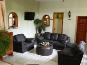 sala de estar con muebles de cuero negro y TV en Hotel el Leñador, en Mazamitla