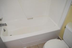 a white bath tub sitting next to a white toilet at White Oaks Motel Pennsville/Carneys Point in Pennsville