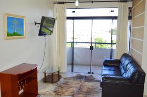 a living room with a leather couch and a television at Hotel Rota do Pantanal in Presidente Prudente
