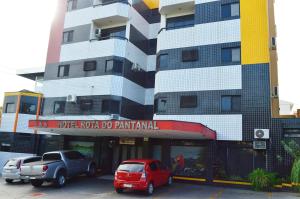 two cars parked in front of a building at Hotel Rota do Pantanal in Presidente Prudente