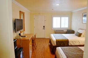 a hotel room with two beds and a desk and a television at Wittle Motel in Sunnyvale