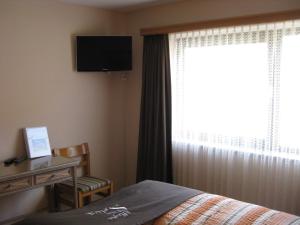 Schlafzimmer mit einem Bett, einem Schreibtisch und einem Fenster in der Unterkunft Hotel Pizzeria Selva in Zernez