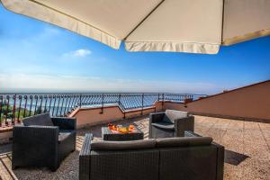 a patio with chairs and tables and an umbrella at Mansarda sopra il mare in San Marco dʼAlunzio