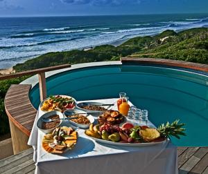 a table with plates of food on a table with the beach at Massinga Beach in Massinga