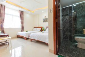 ブンタウにあるBiển Ngọc Hotelのベッドルーム1室(ベッド2台、ガラス張りのシャワー付)