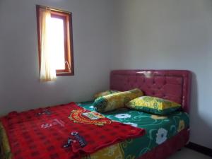 Bett mit rotem Kopfteil und Kissen darauf in der Unterkunft Agung Safira Homestay in Bromo