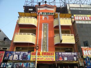 ein hohes orangefarbenes Gebäude mit Balkonen an einer Stadtstraße in der Unterkunft Hotel Everest in Hyderabad