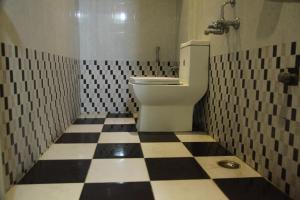 ein Badezimmer mit einem WC und einem schwarz-weiß karierten Boden in der Unterkunft Hotel Everest in Hyderabad
