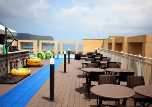 a swimming pool with tables and chairs on a balcony at Ktree Jeju Seongsan Hotel in Seogwipo