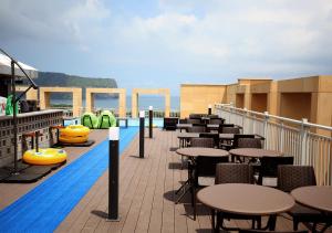 a swimming pool with tables and chairs on a balcony at Golden Tulip Jeju Seongsan Hotel in Seogwipo